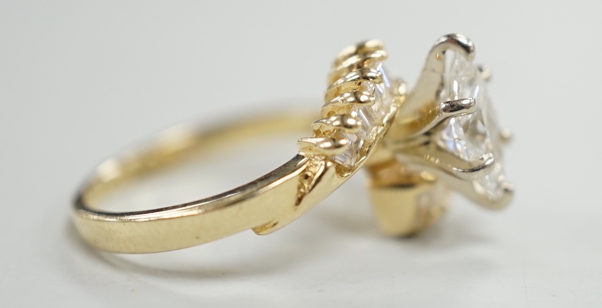 A yellow metal and singe stone marquise cut diamond set crossover dress ring, with baguette cut diamond set shoulders, size J/K, gross weight 3.2 grams.